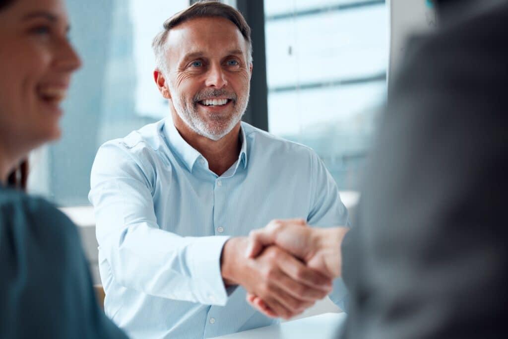 business man shaking hands in divestiture meeting